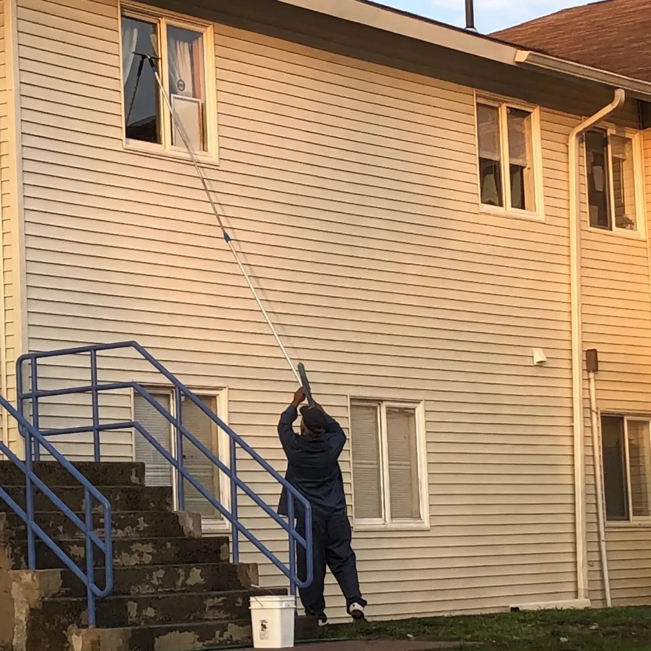 Burgos Cleaning team member cleaning exterior windows from the ground with a pole