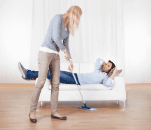 woman cleaning the floor and man lying in the couch