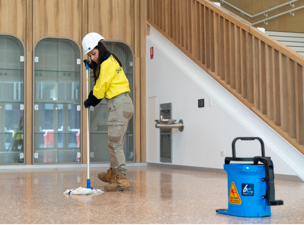 a woman in a hard hat mopping the floor
