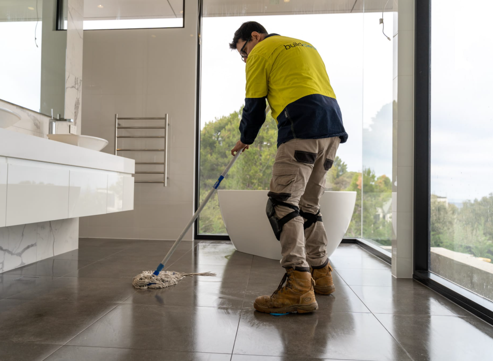 a man mopping the floor in a bathroom